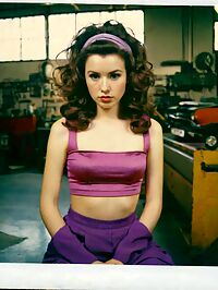 Lady emerges in the dimly lit auto repair shop 1950s era style surrounding her slender frame